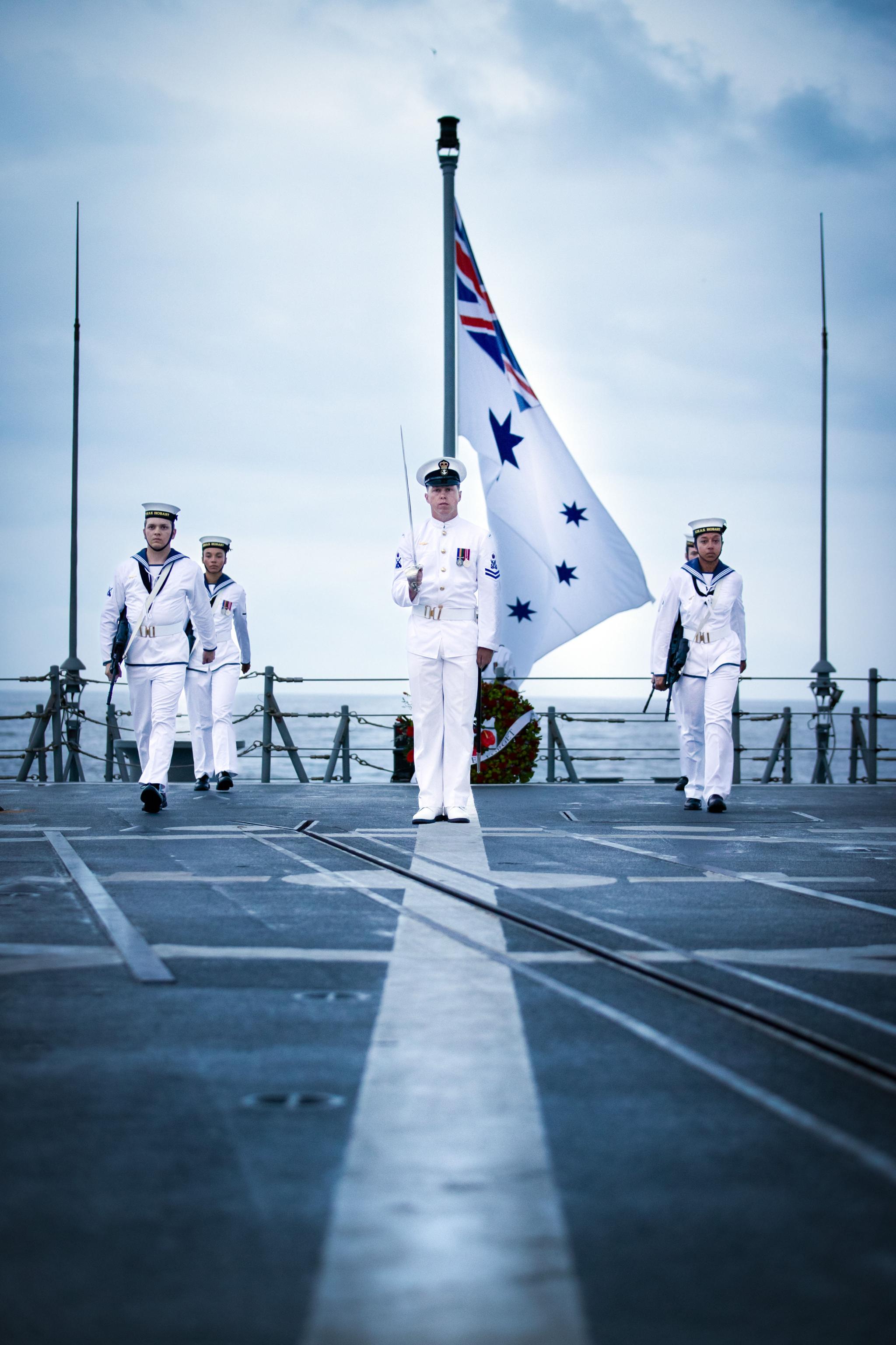 The catafalque party marches off to retire on the flight deck of HMAS Hobart as the ship sails through the South China Sea as part of a Regional Presence Deployment.