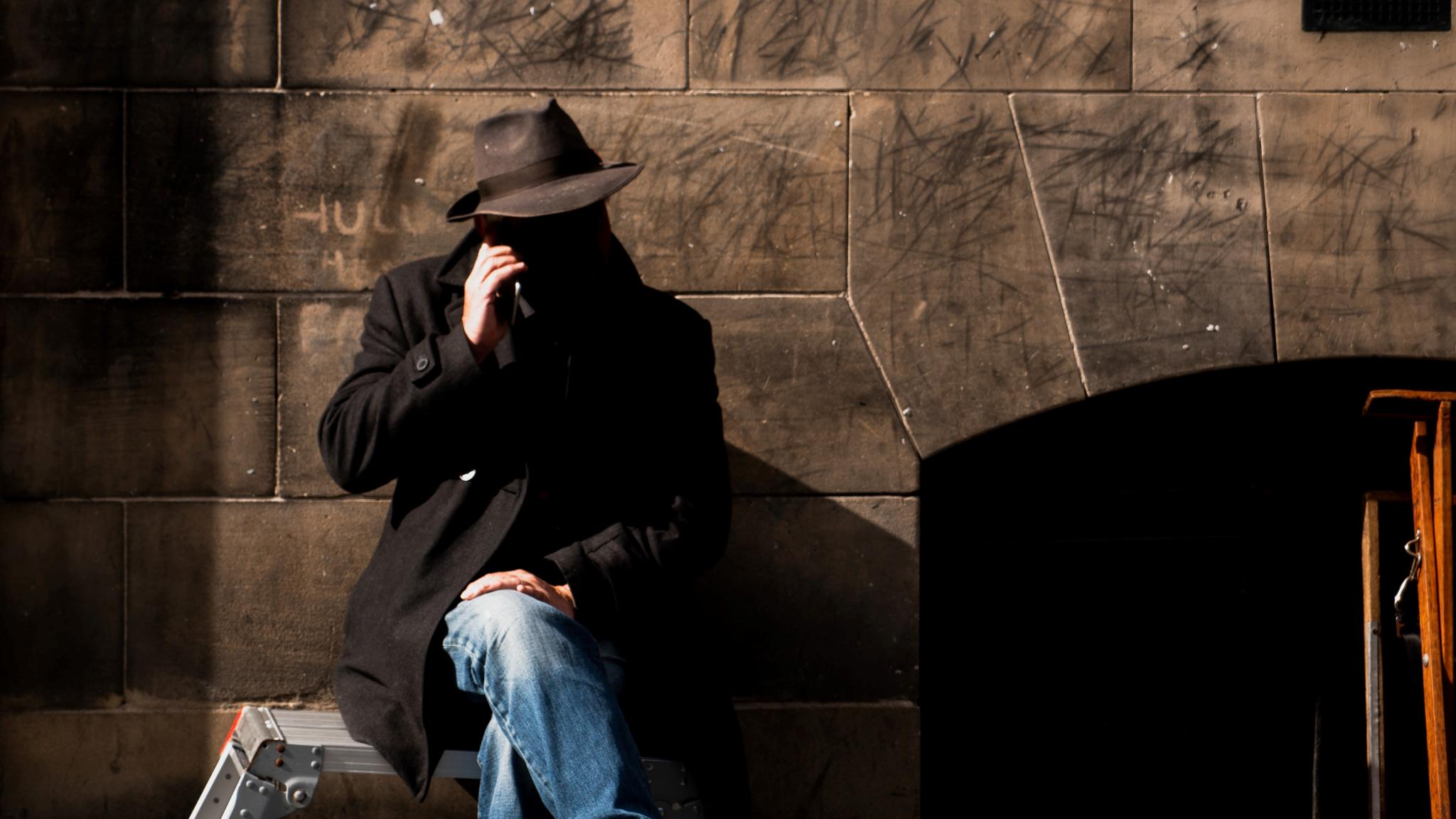 Spy sitting on bench conducting phone tapping