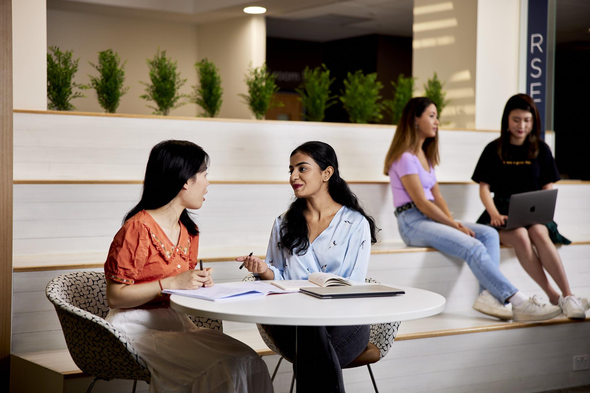 Two women sitting at table discussing papers.