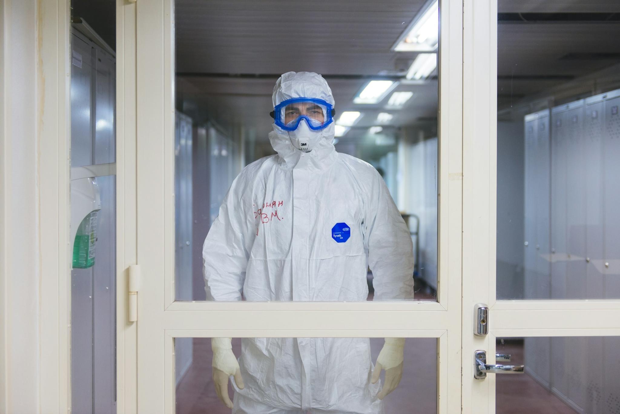 Person wearing a white hazard suit and gloves