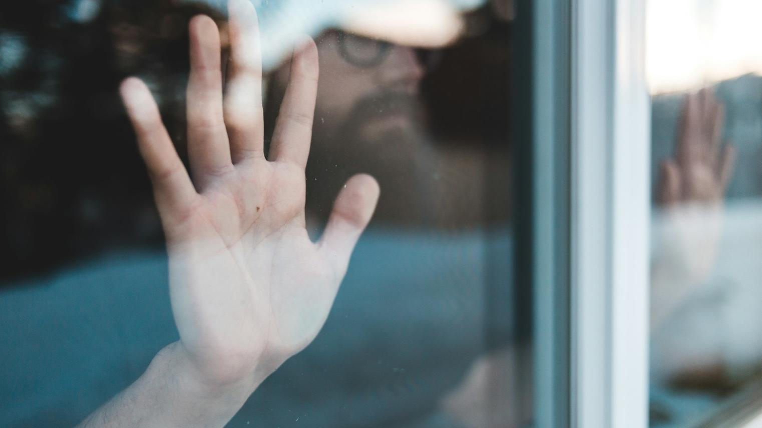 A persons hand on a glass window