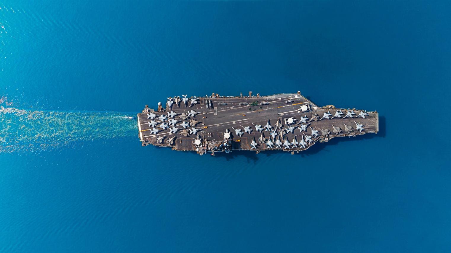 Aerial top view military navy ship carrier at sea.
