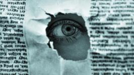 Eye poking out of a newspaper hole